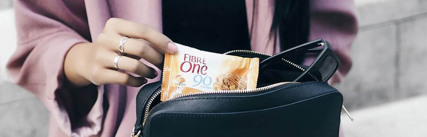 A woman taking a Fibre One 90 Calorie bar out of her handbag.